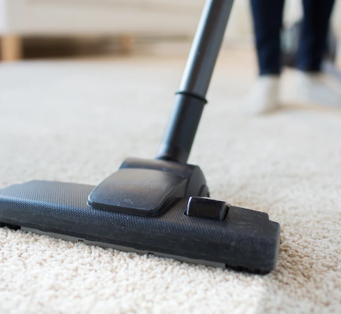 Person using commercial vacuum to clean carpet